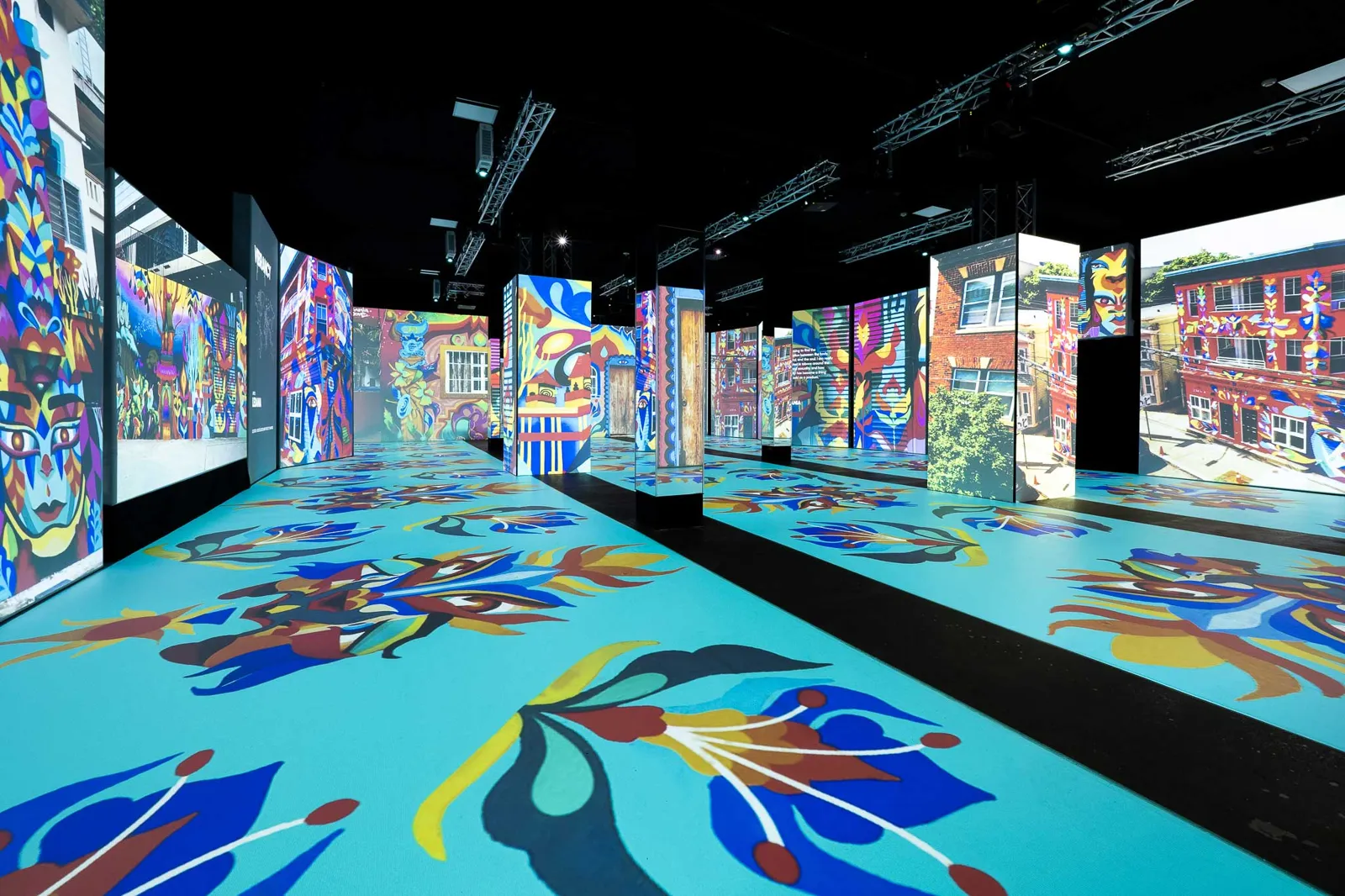 Colorful floral street art projected across the floor and walls of a dark hall
