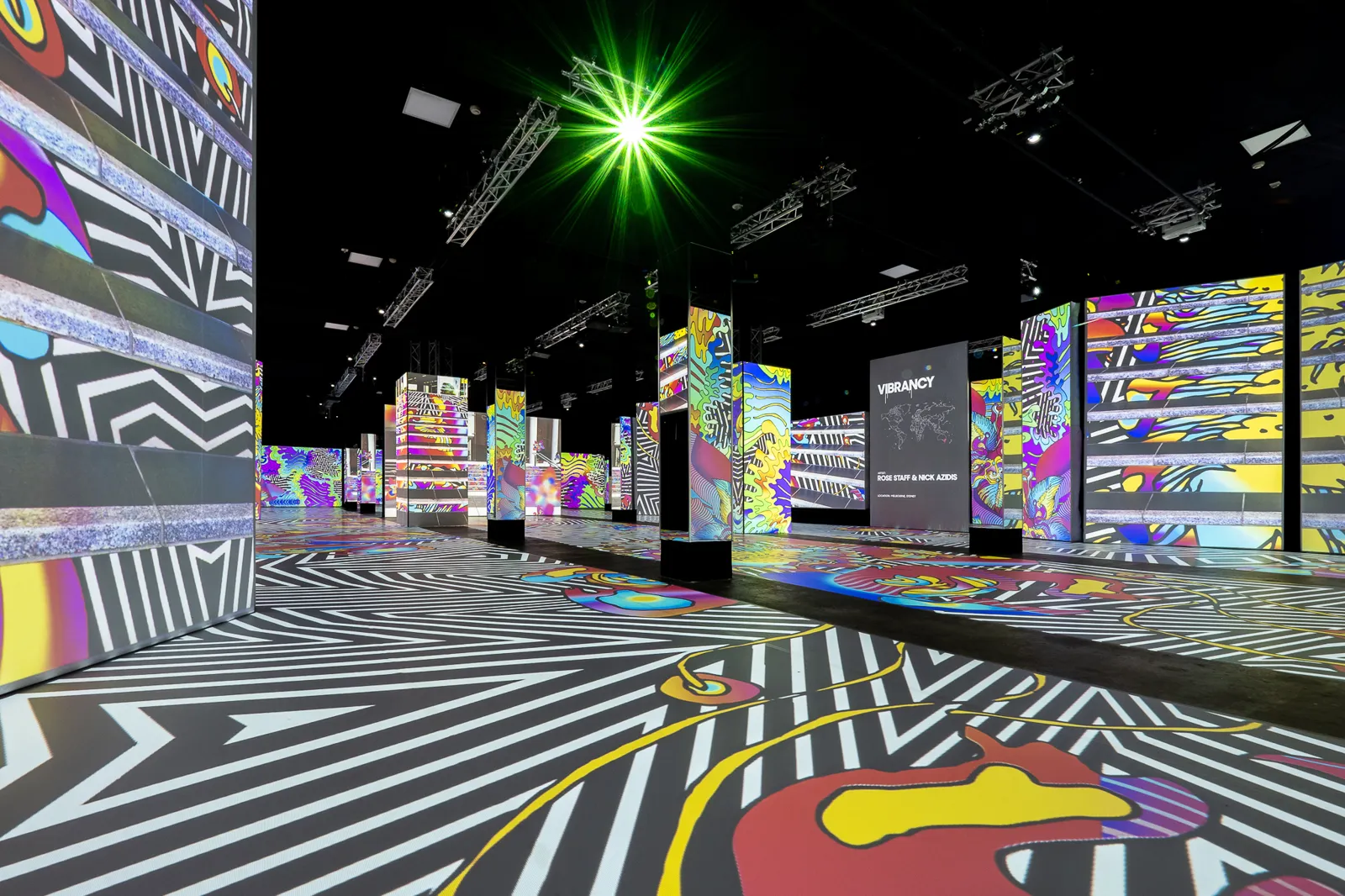 Black and white zigzag projections across panels and the floor of a dark hall