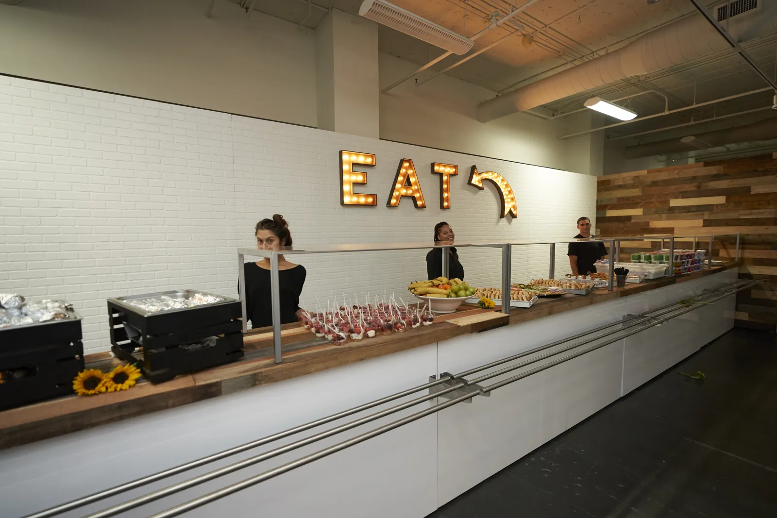 Food counter with trays of snacks under a lit marquee sign