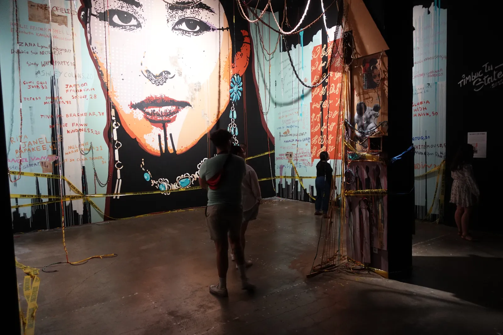 Large mural of a woman's face in a dim hall as a person walks past