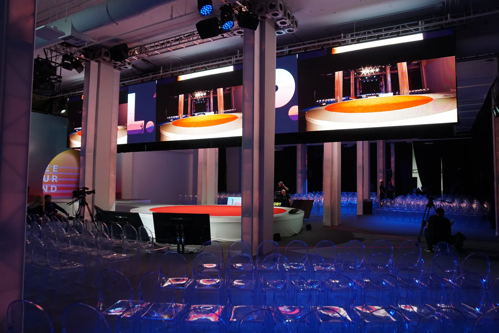 Empty conference hall with clear chairs facing a round red stage