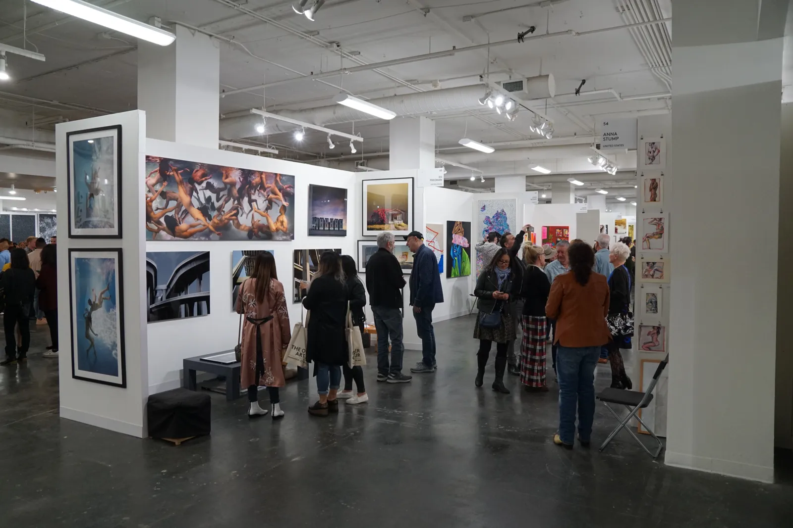 Art fair crowd browsing framed photographs on white gallery walls