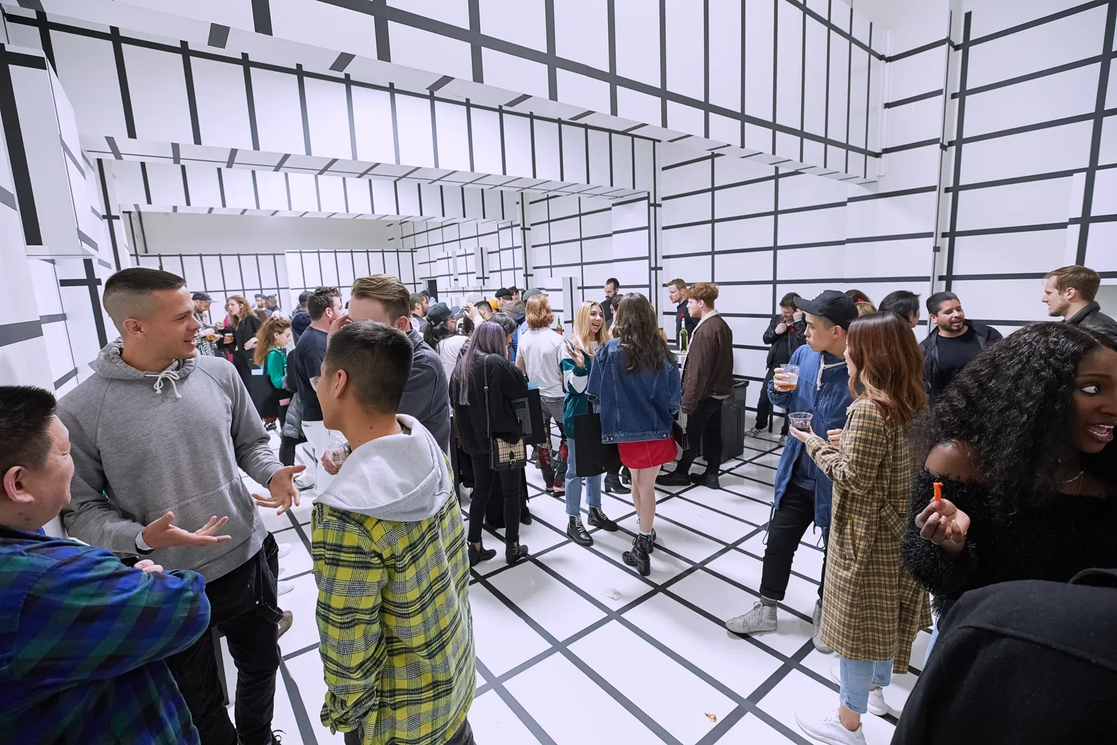 Guests mingling inside a white room covered in black grid lines