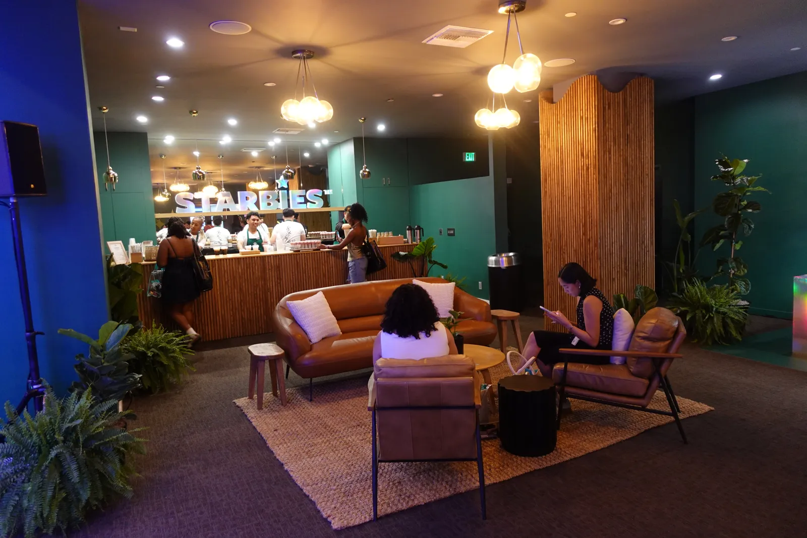 Warm lounge with leather sofas, plants and pendant lights by a bar