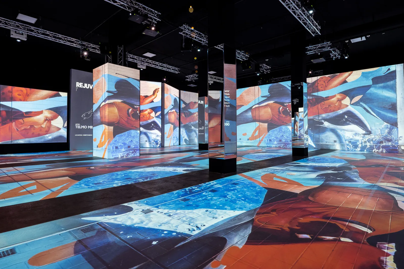 Blue and orange street art projected across the floor and freestanding panels