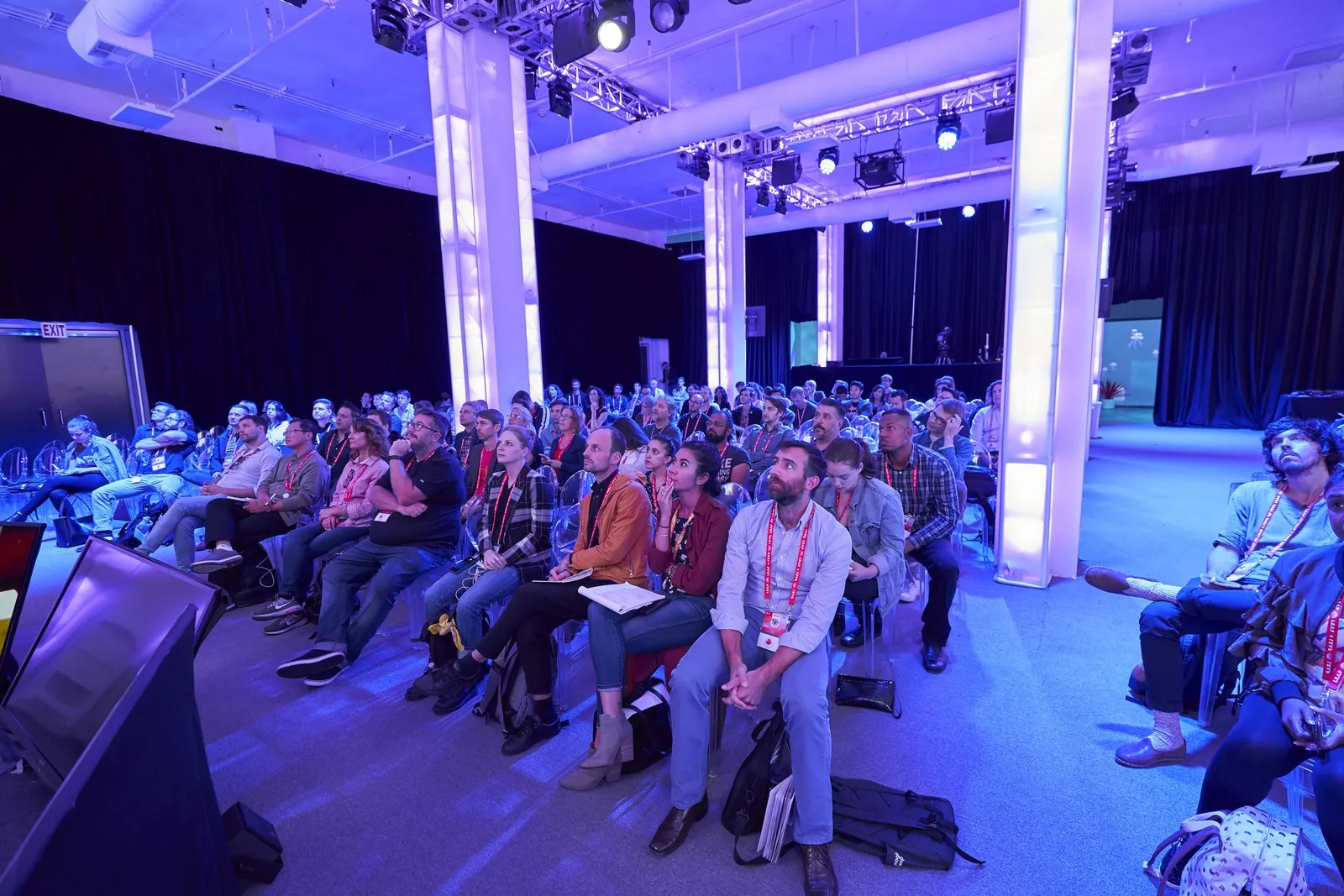 A packed audience under blue stage lights at a conference